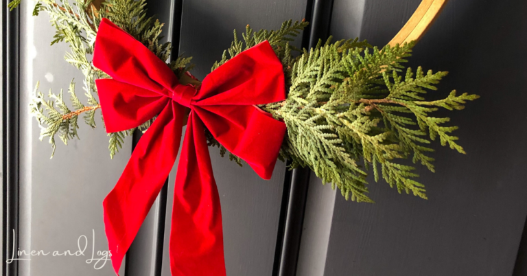 close up picture of hoop christmas wreath with cedar branches and red bow