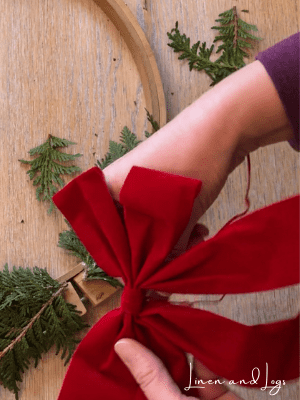 Attaching red bow to embroidery hoop wreath