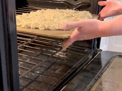 putting baking stone with rieska dough on baking stone into the oven