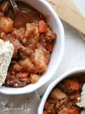 beef stew in white bowl with side of bread