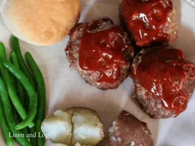 bbq meatballs with bbq sauce. Red potatoes, bread roll, and green beans on the side