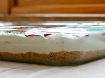 cheesecake dessert in 9x13 dish showing the layers of graham cracker crust, cheesecake layer, and berries