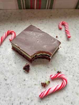 a bar of peppermint brownie with a bite taken out. Chocolate layer on top, green frosting in the middle, and fudge brownie
