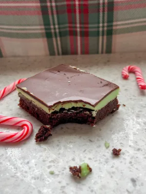 a bar of peppermint brownie with a bite taken out. Chocolate layer on top, green frosting in the middle, and fudge brownie
