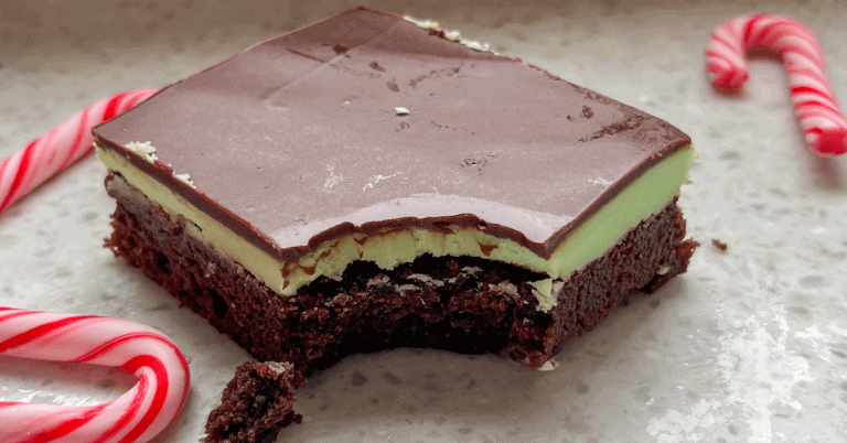 one peppermint christmas brownie - with a bite taken out. Layered fudge brownie with a middle layer of green peppermint frosting and a top layer of chocolate.