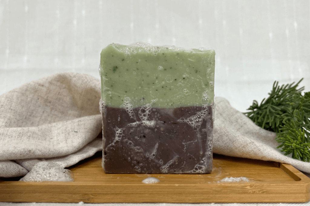 bar of northern woods tallow soap made by linen and logs - bubbles on a soap bar green on top and brown on bottom